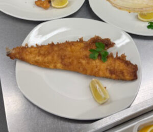 Beef dripping battered fish with a garnish of lemon and parsley.