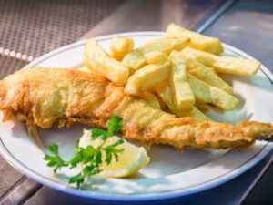 Plate of beef dripping battered fish and chips with a lemon and parsley garnish