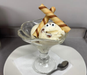 Scoops of ice cream in a sundae glass with two swirl wafers and edible eyes to make the ice cream look fun and quirky