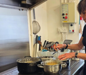 Jane inside the kitchen cooking at the hob