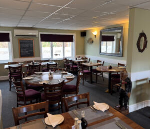 Picture of the inside layout of Janes Upstairs, wooden chairs, green walls with fish decor. Tablets set with placemats, cutlery and plates with salt and vinegar