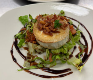 Pie with lardon and balsamic garnish on a bed of lettuce