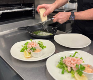 Asparagus being prepared in the pan by the chef with other plates of prawns and seafood sauce waiting to go out to our lovely customers.