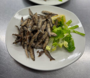 White bait on a plate with lettuce and a garnish of lemon slice